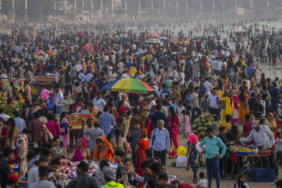 People crowd at the Juhu beach on the Arabian Sea coast in Mumbai, India, Sunday, Nov. 13, 2022. The 8 billionth baby on Earth is about to be born on a planet that is getting hotter. But experts in climate science and population both say the two issues aren't quite as connected as they seem. (AP Photo/Rafiq Maqbool)