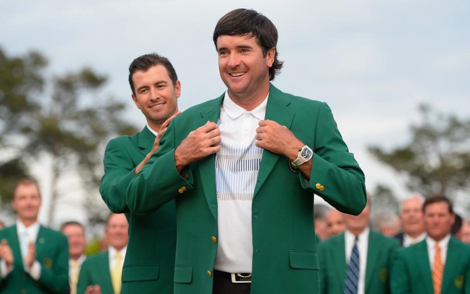 Adam Scott of Australia presents the green jacket to Bubba Watson of the United States after Watson won the 2014 Masters Tournament by three strokes at Augusta National Golf Club in Augusta, Georgia, on April 13, 2014.