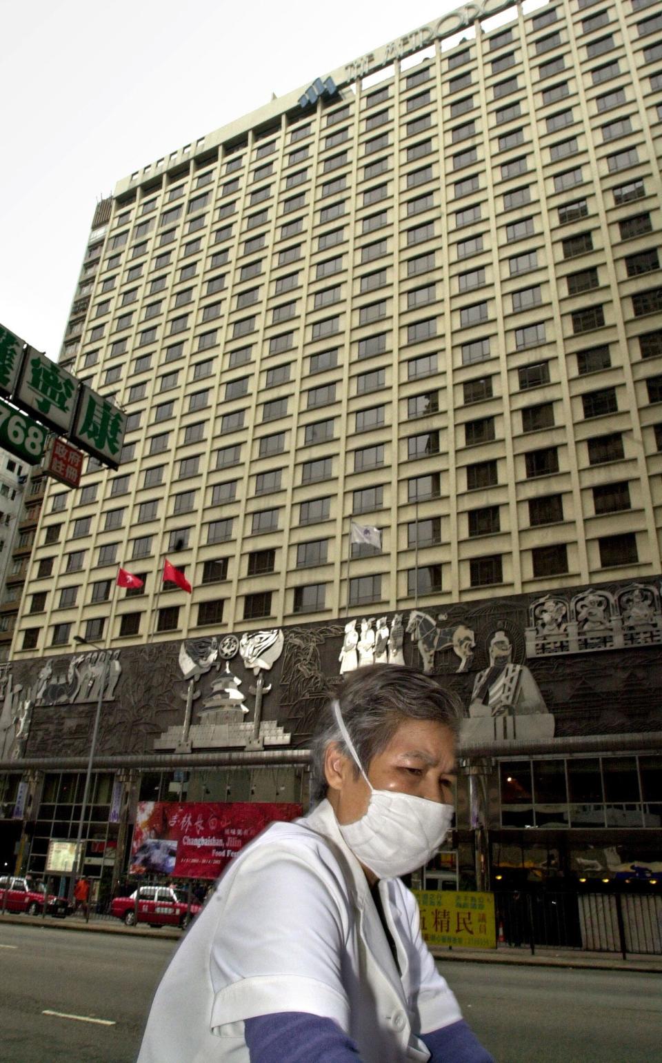 A hygiene worker wearing a protective mask passes Thursday, March 20, 2003 by Metropole Hotel in Hong Kong