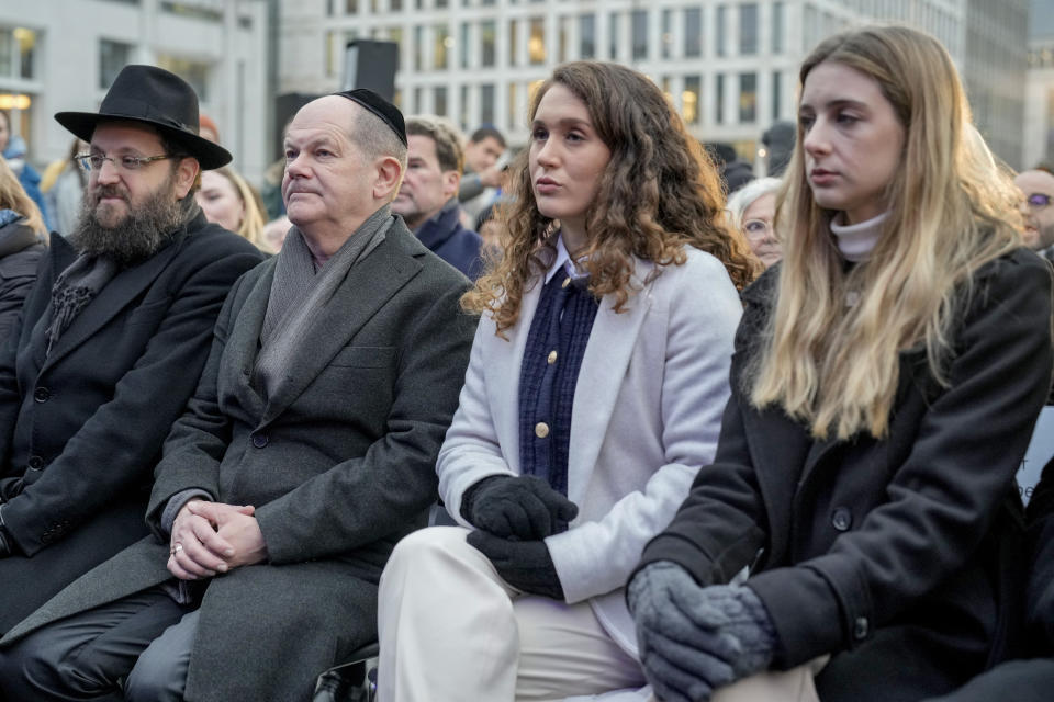 German Chancellor Olaf Scholz, 2nd left, Rabbi Yehuda Teichtal, left, Naama Weinberg, 2nd right, and Ofir Weinberg, right, both cousins of Hamas hostage Itay Svirsky attend the ceremony to light the first candle of Hanukkah menorah at Brandenburg Gate in Berlin, Germany, Thursday, Dec. 7, 2023. (AP Photo/Markus Schreiber)