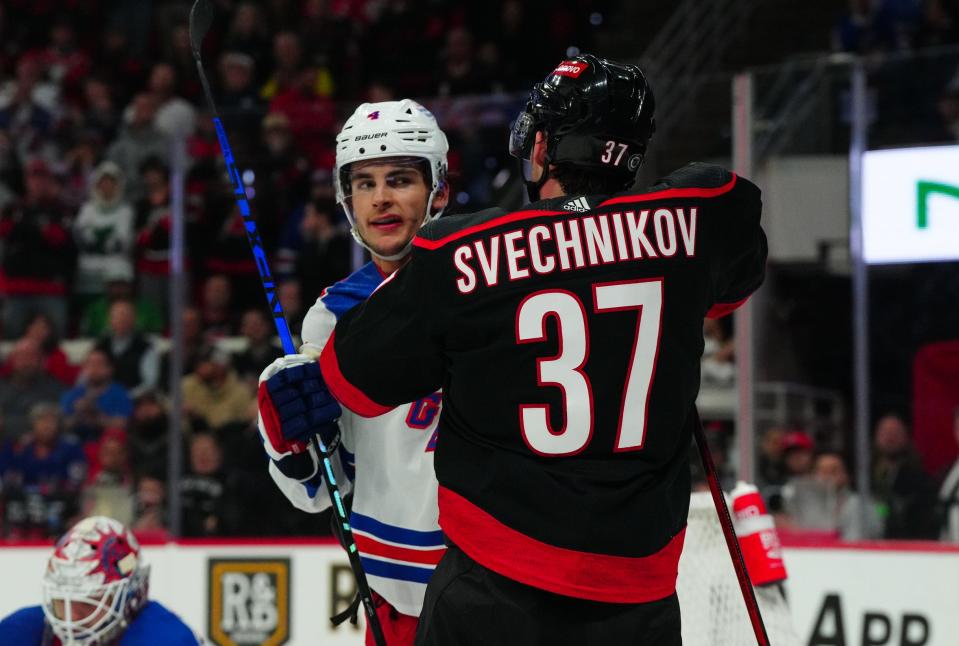 Mar 12, 2024; Raleigh, North Carolina, USA; New York Rangers defenseman Braden Schneider (4) and Carolina Hurricanes right wing Andrei Svechnikov (37) battle in the third period at PNC Arena.