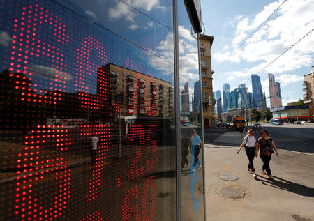 Pedestrians walk past an electronic board showing currency exchange rates of the U.S. dollar and euro against Russian rouble in Moscow, Russia August 10, 2018. REUTERS/Maxim Shemetov