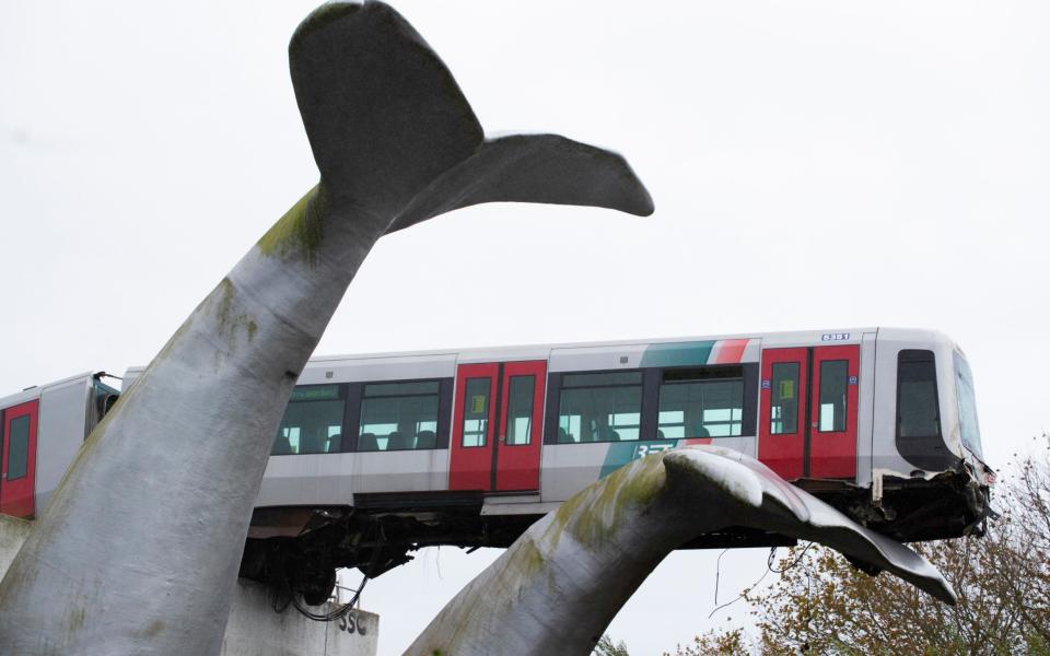 The whale's tail of a sculpture caught the front carriage of a metro train as it rammed through the end of an elevated section of rails - AP