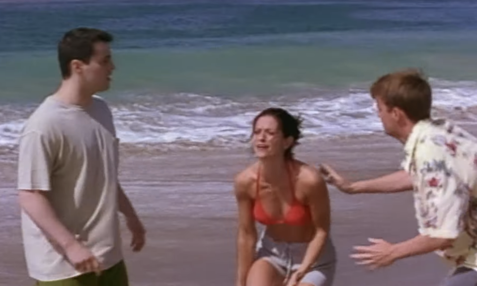 A woman clenching her leg in pain by the beach