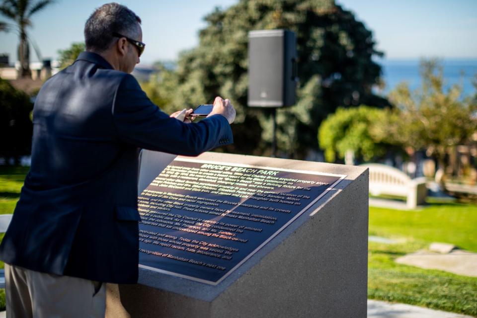 A man takes a cellphone photo of a plaque