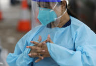 A woman prepares to test drivers at a drive through COVID-19 testing station at a beach in Sydney, Australia, Saturday, Dec. 19, 2020. Sydney's northern beaches will enter a lockdown similar to the one imposed during the start of the COVID-19 pandemic in March as a cluster of cases in the area increased to more than 40. (AP Photo/Mark Baker)