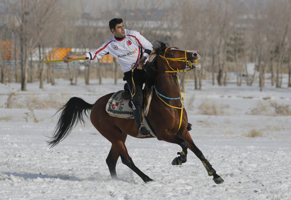 A rider prepares to throw the javelin during a game of Cirit, a traditional Turkish equestrian sport that dates back to the martial horsemen who spearheaded the historical conquests of central Asia's Turkic tribes, between the Comrades and the Experts local sporting clubs, in Erzurum, eastern Turkey, Friday, March 5, 2021. The game that was developed more than a 1,000 years ago, revolves around a rider trying to spear his or her opponent with a "javelin" - these days, a rubber-tipped, 100 centimeter (40 inch) length of wood. A rider from each opposing team, which can number up to a dozen players, face each other, alternately acting as the thrower and the rider being chased. Cirit was popular within the Ottoman empire, before it was banned as in the early 19th century. However, its popularity returned as is now one of many traditional sports encouraged by the government and tournaments are often arranged during festivals or to celebrate weddings. (AP Photo/Kenan Asyali)