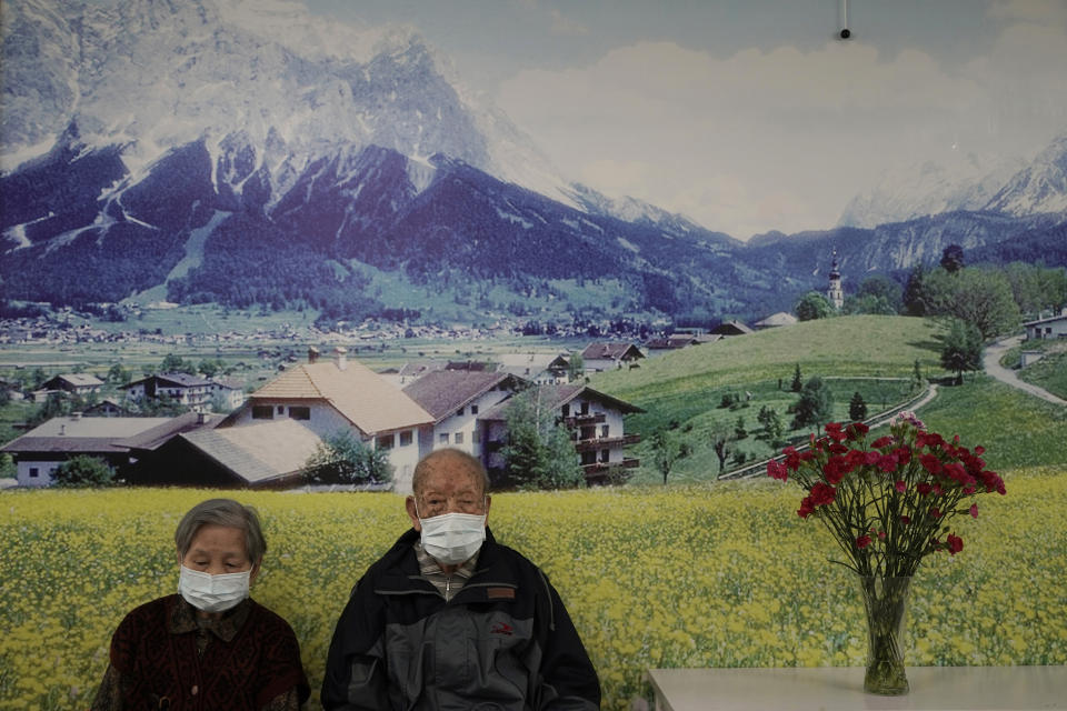 Elderly couple wearing protective face masks sit at a nursing home on Valentine's Day in Hong Kong, Friday, Feb. 14, 2020. China on Friday reported another sharp rise in the number of people infected with a new virus, as the death toll neared 1,400. (AP Photo/Kin Cheung)