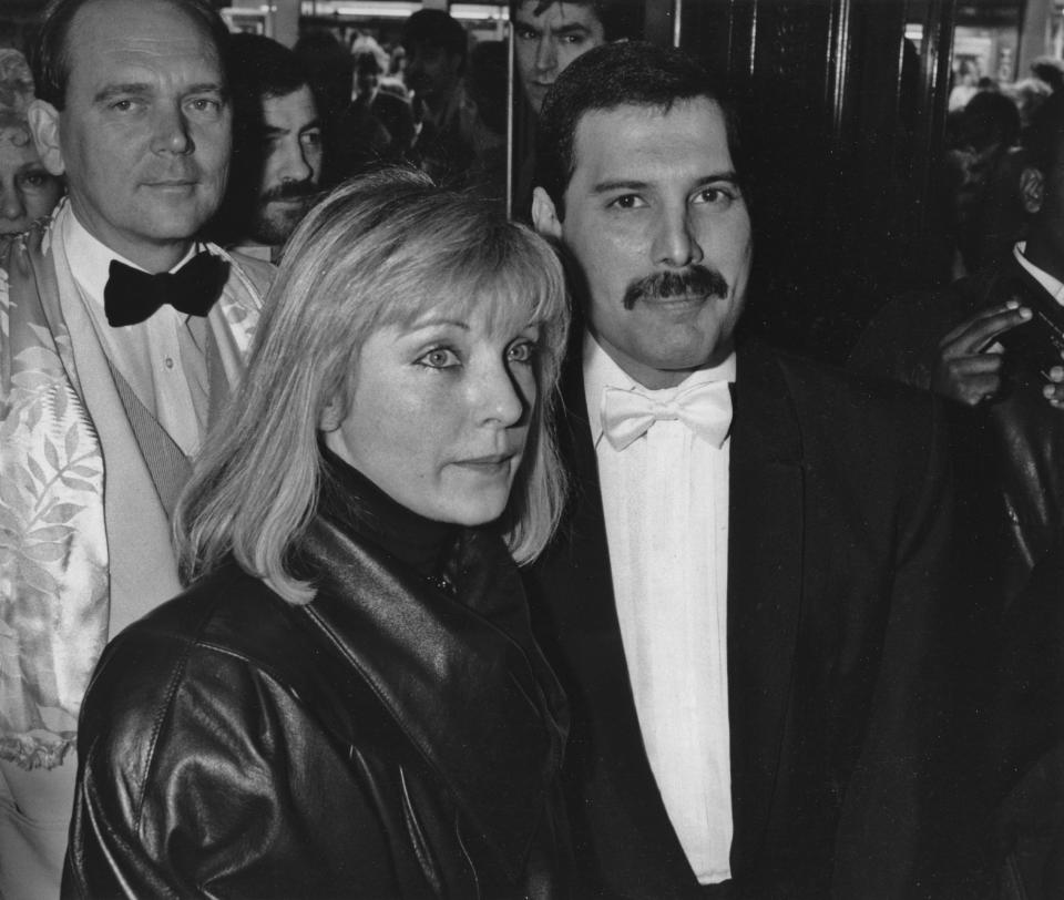 Singer Freddie Mercury (1946 - 1991) of British rock band Queen with his friend Mary Austin at an after-party in London for 'Dave Clark's Time - The Musical', 9th April 1986. Behind them is Queen's manager Jim Beach, . (Photo by Dave Hogan/Getty Images)