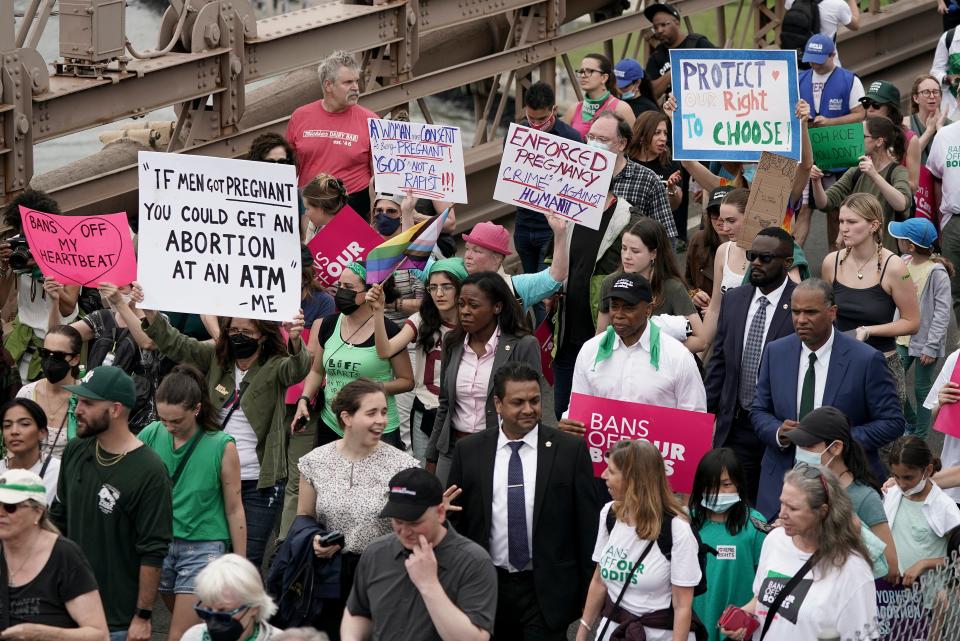 New York City Mayor Eric Adams, wearing a black cap and carrying a pink sign, marches with abortion-rights activists on May 14, 2022, in New York. Adams was asked at the rally whether he believed that there should be any limitations on abortion. He answered: "No, I do not." And he added: "I think women should have the right to choose their bodies. Men should not have that right to choose how a woman should treat their body."