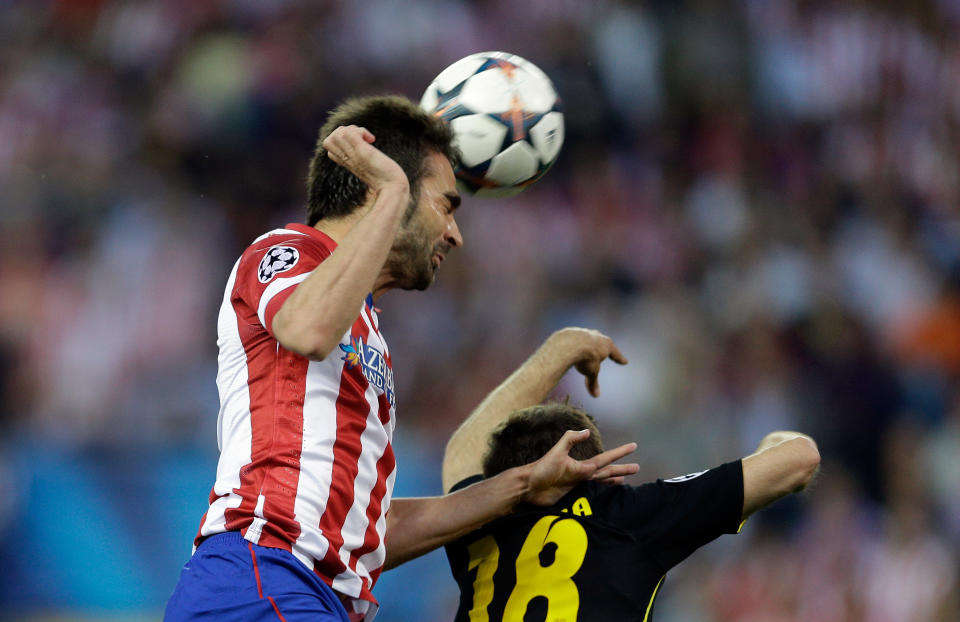 Atletico's Adrian Lopez, left, heads the ball for teammate Koke to score the opening goal during the Champions League quarterfinal second leg soccer match between Atletico Madrid and FC Barcelona in the Vicente Calderon stadium in Madrid, Spain, Wednesday, April 9, 2014. (AP Photo/Paul White)