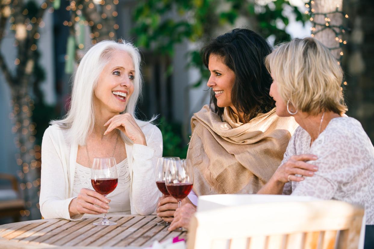 group of middle-aged women drinking wine outside on restaurant patio