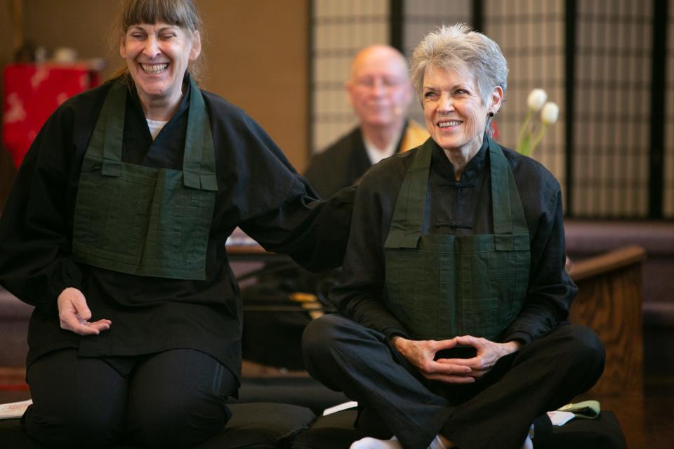 Tina Nepstad-Thornberry, left, and Vicki Goldsmith react during lay a entrustment ceremony at the Des Moines Zen Center in Des Moines, IA.
