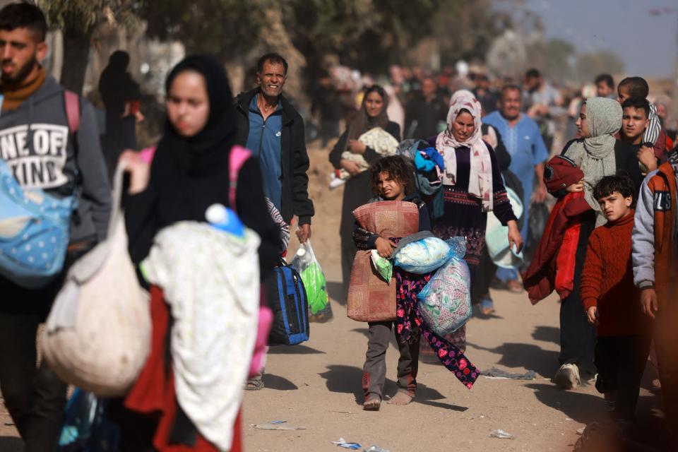 Palestinians fleeing Gaza City and other parts of northern Gaza carry some belongings as they walk along a road leading to the southern areas of the enclave on Nov. 18, 2023, amid ongoing battles between Israel and the Palestinian Hamas movement.