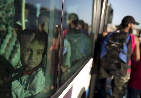 A migrant child is seen through a bus window following his arrival onboard the Eleftherios Venizelos passenger ship at the port of Piraeus near Athens, Greece, August 29, 2015. REUTERS/Stoyan Nenov