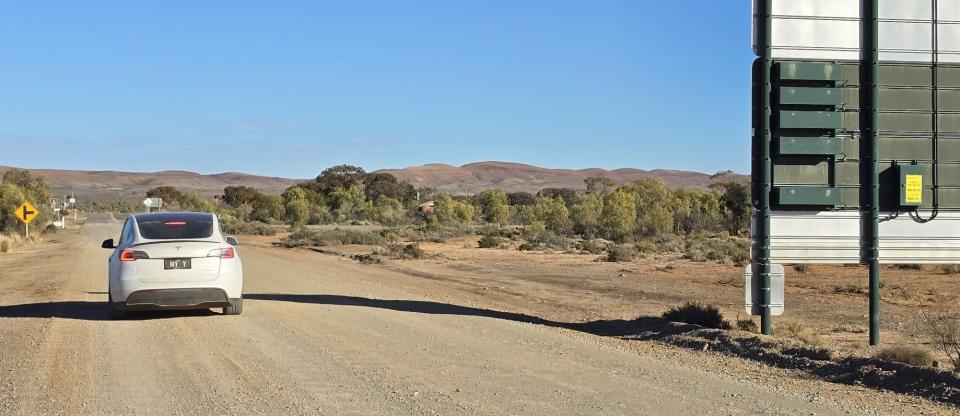 A Tesla model Y pictured driving on a dusty road in remote Western Australia.