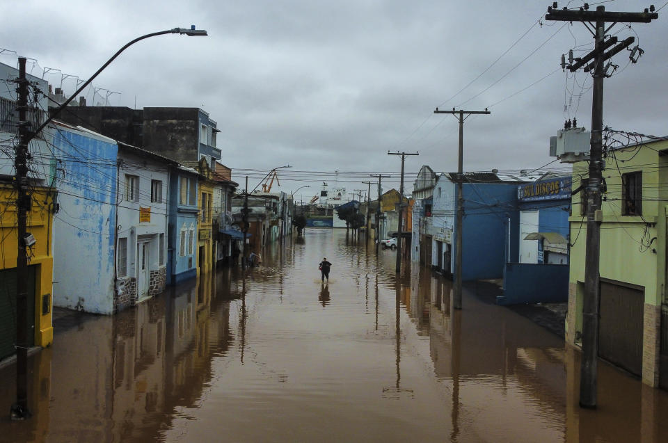 A man wades an area flooded by heavy rains, in Porto Alegre, Rio Grande do Sul state, Brazil, Friday, May 3, 2024. (AP Photo/Carlos Macedo)