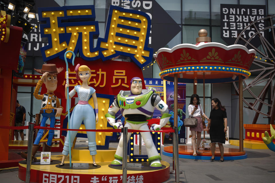 A woman browses her photo after taking with her friend near the American latest animated film "Toy Story 4" promotion decoration on display at the capital city's popular shopping mall in Beijing, Tuesday, June 25, 2019. China says its trade negotiators are talking to their U.S. counterparts on how to resolve disputes ahead of an expected meeting between their two heads of state at the G20 meeting in Japan later this week. (AP Photo/Andy Wong)