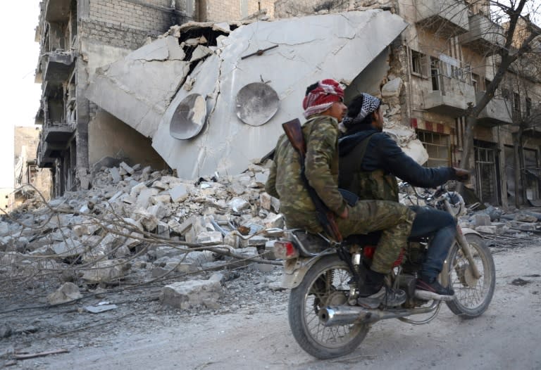 Rebels ride a motorcycle past a destroyed building in the northwestern Syrian border town of al-Bab on February 25, 2017