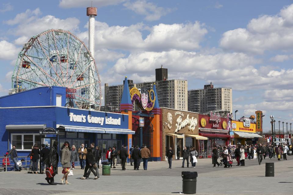 In a Saturday March 30, 2013, photo visitors to New York's Coney Island walk on the boardwalk past the open businesses. Despite making the traditional Palm Sunday opening, many of the seasonal businesses at Coney Island are still reeling from the aftermath of Superstorm Sandy. (AP Photo/Mary Altaffer)