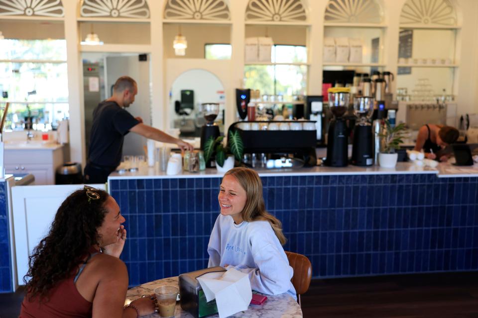 Customers Genevieve Clelland, left, and Julia Holt enjoy coffee and conversation at newly opened DOS Coffee & Wine in Town Center Plaza, adjacent to St. Johns Town Center. DOS Coffee & Wine shares the storefront with Mayday Handcrafted  Ice Cream.