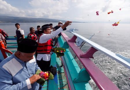 Villagers and Muslim clerics throws flowers after praying for the missing passengers, after a ferry sank earlier this week in Lake Toba in Simalungun, North Sumatra, Indonesia, June 22, 2018. REUTERS/Beawiharta