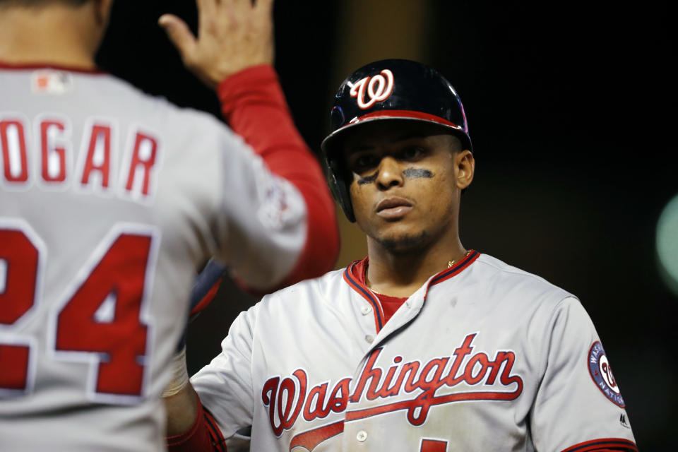 Washington Nationals first base coach Tim Bogar, front, congratulates Wilmer Difo after he singled to drive in two runs off Colorado Rockies relief pitcher Jake McGee in the seventh inning of a baseball game Saturday, Sept. 29, 2018, in Denver. (AP Photo/David Zalubowski)