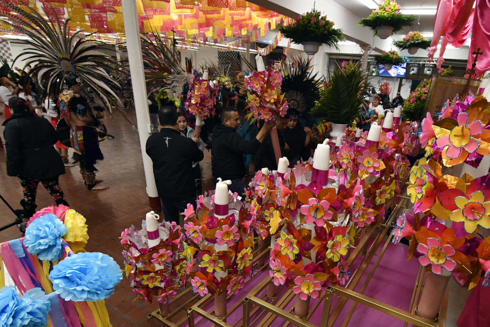 In this Jan. 24, 2020 photo, three-foot tall handmade wax candles studded with pink and yellow flowers are shown inside the Sagrado Corazon de Jesus church in Minneapolis. The wax candles were made by people celebrating the patron saint of their Mexican hometown of Axochiapan and nearby villages in the state of Morelos as a way to recognize their roots and feel closer to the families and home they left behind. (AP Photo/Jim Mone)