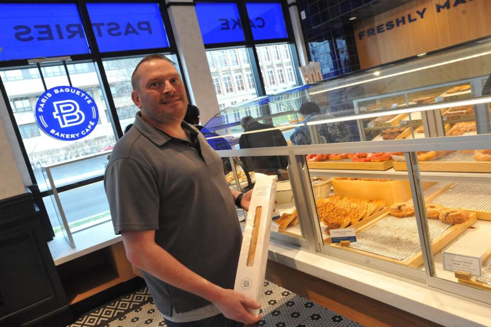 District manager Brice Sauers holds a freshly wrapped baguette at the new Paris Baguette on Hancock Street in North Quincy, Sunday, Dec. 10, 2023.