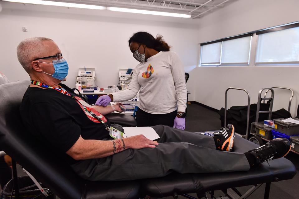 Jabarra Woodson, phlebotomist, checks on Shaun Brennan as he donates blood for the 502nd time at the American Red Cross in Memphis on Nov. 11, 2021.