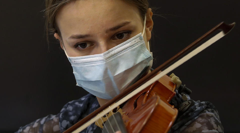 Hildegard De Stefano wears a face mask to curb the spread of COVID-19 as she plays her violin during a lesson with maestro Luca Braga at the Giuseppe Verdi Music Conservatory, in Milan, Italy, Thursday, April 29, 2021. Whatever the instrument, flute, violin or drums, students at Italy's oldest and largest music conservatory have been playing behind plexiglass screens during much of the pandemic as the Conservatory found ways to preserve instruction throughout Italy’s many rolling lockdowns. (AP Photo/Antonio Calanni)