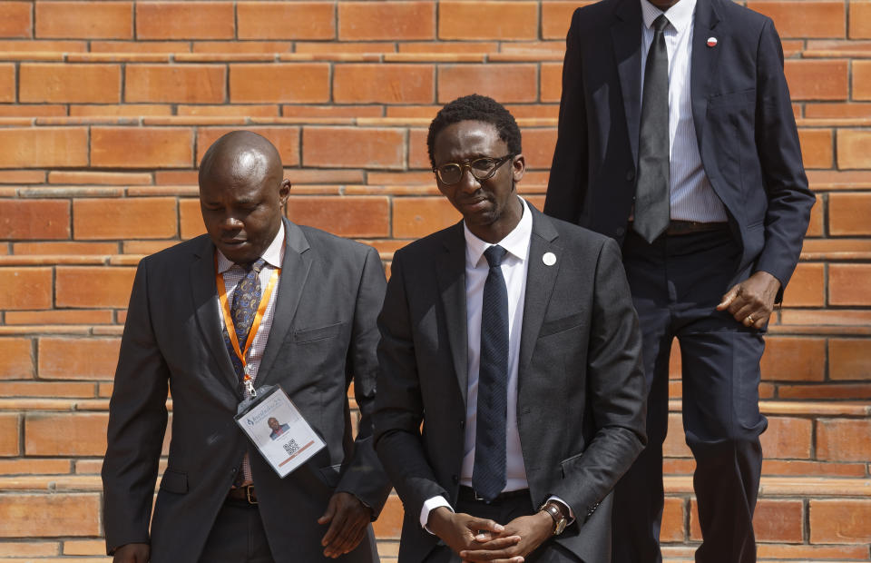 Rwandan-born French MP Herve Berville, center, representing France, arrives to lay a wreath at the Kigali Genocide Memorial in Kigali, Rwanda Sunday, April 7, 2019. Rwanda is commemorating the 25th anniversary of when the country descended into an orgy of violence in which some 800,000 Tutsis and moderate Hutus were massacred by the majority Hutu population over a 100-day period in what was the worst genocide in recent history. (AP Photo/Ben Curtis)