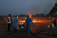 Relatives stand near the funeral pyre of their loved one who died due to COVID-19 at a cremation ground in Prayagraj, India, Saturday, May 8, 2021. (AP Photo/Rajesh Kumar Singh)