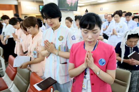 Hospital workers pray during a mass to wish for patients suffering from Middle East Respiratory Syndrome (MERS) to get better, at a hospital in Seoul, South Korea, June 12, 2015. REUTERS/Park Ji-ho/Yonhap