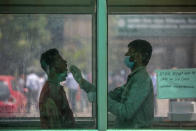 A health worker takes a swab sample to test for COVID-19 at a government hospital in Noida, a suburb of New Delhi, India, Thursday, April 15, 2021. India reported more than 200,000 new coronavirus cases Thursday, skyrocketing past 14 million overall as an intensifying outbreak puts a grim weight on its fragile health care system. (AP Photo/Altaf Qadri)