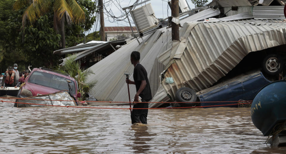 A resident walking through a flooded street looks back at storm damage in a neighbourhood of Planeta, Honduras on November 6.