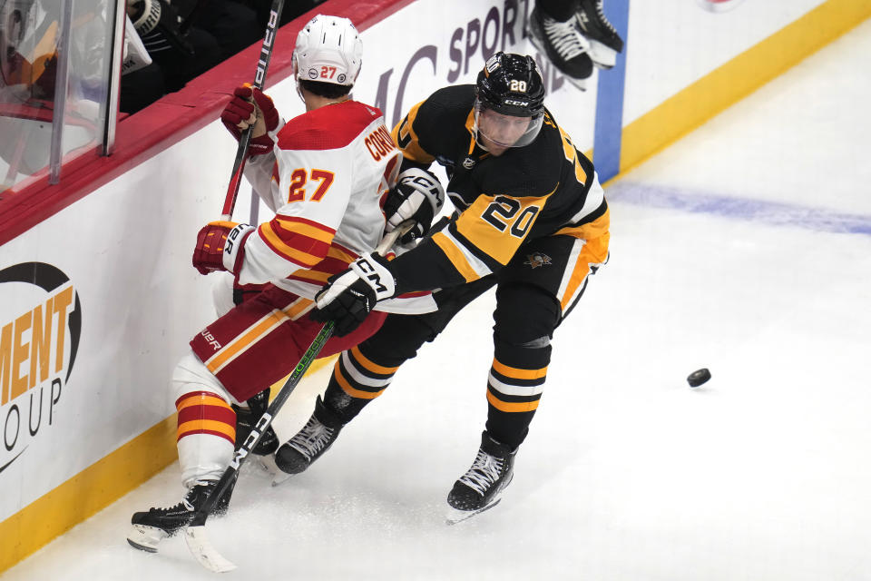 Pittsburgh Penguins' Lars Eller (20) checks Calgary Flames' Matt Coronato off the puck during the first period of an NHL hockey game in Pittsburgh, Saturday, Oct. 14, 2023. (AP Photo/Gene J. Puskar)