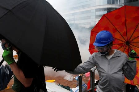 Protesters wearing masks and holding umbrellas are seen near tear gas during a demonstration against a proposed extradition bill, in Hong Kong