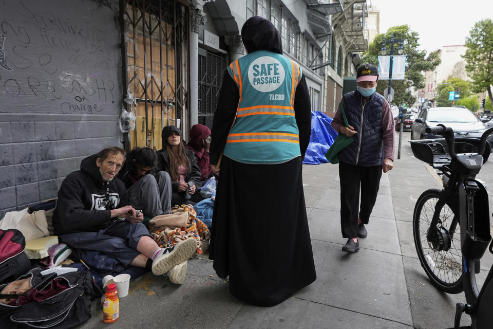 Tatiana Alabsi, center, talks to a group of people sitting on a sidewalk in the Tenderloin neighborhood Wednesday, April 24, 2024, in San Francisco. (AP Photo/Godofredo A. Vásquez)