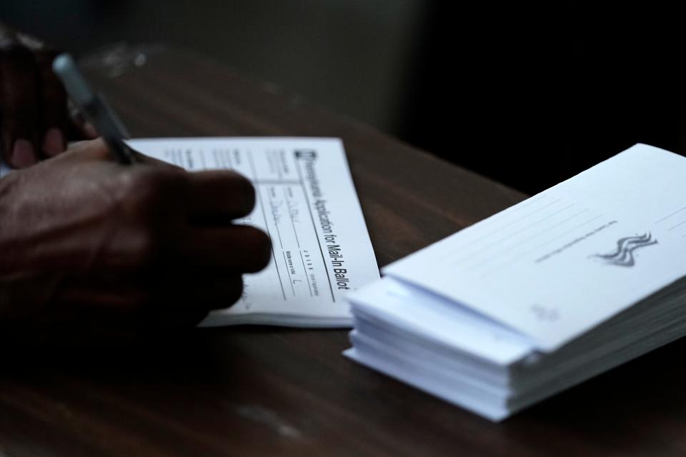 Philadelphia City Council President Darrell L. Clarke fills out an application for a mail-in ballot before voting at the opening of a satellite election office at Temple University's Liacouras Center in Philadelphia. Sept. 29, 2020.