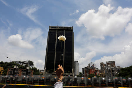 A demonstrator holds up a flower in front of riot policemen during a women's march to protest against President Nicolas Maduro's government in Caracas, Venezuela, May 6, 2017. REUTERS/Carlos Garcia Rawlins