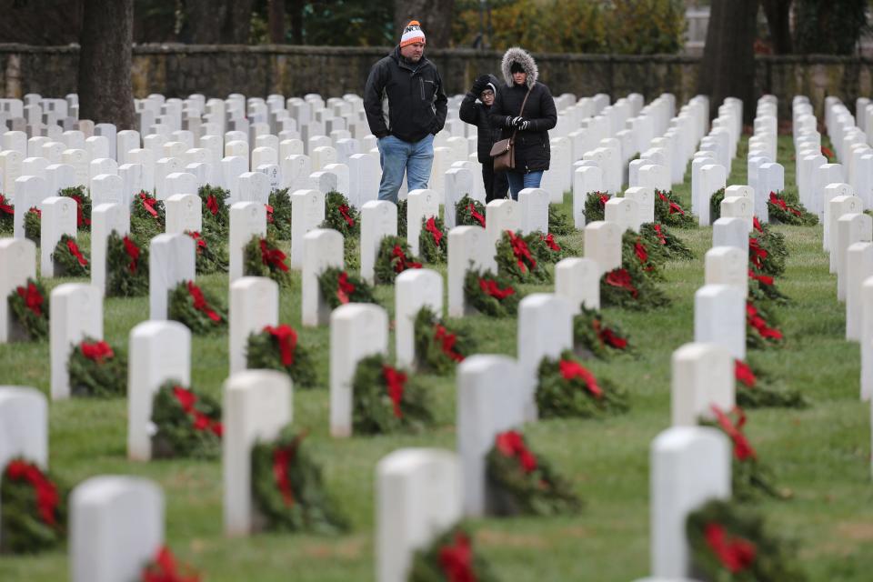 Michael Williams, wife, Melissa, and son, Chase, 12, walk among the headstones after laying wreaths on Saturday.  About a thousand volunteers teamed up to place 6000 wreaths at the graves of soldiers buried at Zachary Taylor National Cemetery on Saturday, December 17, 2022