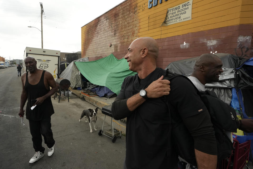 Dr. Kwane Stewart, right, talks to Big Mike, left, as he checks for homeless people's dogs in the Skid Row area of Los Angeles on Wednesday, June 7, 2023. “The Street Vet,” as Stewart is known, has been supporting California's homeless population and their pets for almost a decade. (AP Photo/Damian Dovarganes)