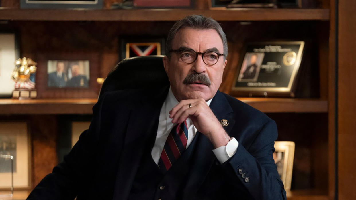  Tom Selleck as Frank Reagan sitting at desk looking serious. 