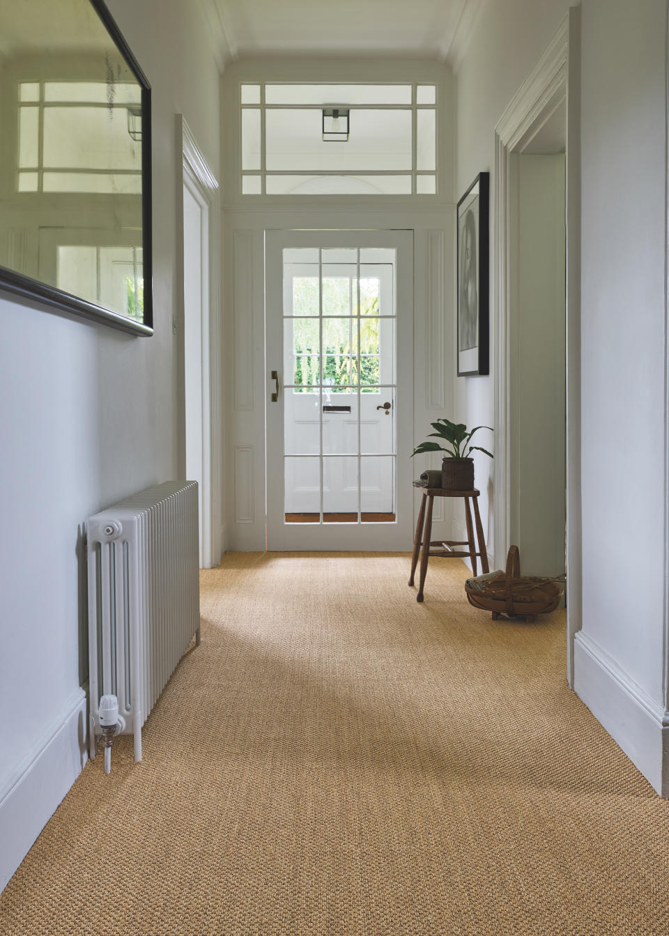 white entryway with sisal flooring, stool, plant, artwork