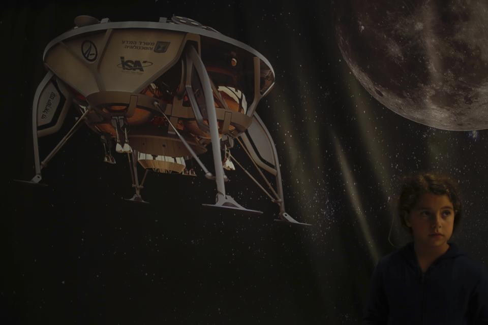 A girl poses for a photo next to a poster of the SpaceIL spacecraft in Netanya, Thursday, April 11, 2019. An Israeli spacecraft has failed in its attempt to make history as the first privately funded lunar mission.The SpaceIL spacecraft lost contact with Earth late Thursday, just moments before it was to land on the moon, and scientists declared the mission a failure. (AP Photo/Ariel Schalit)