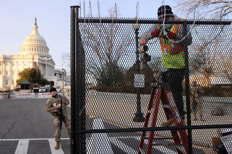 FILE PHOTO: Workers install razor wire atop the unscalable fence surrounding the U.S. Capitol in Washington