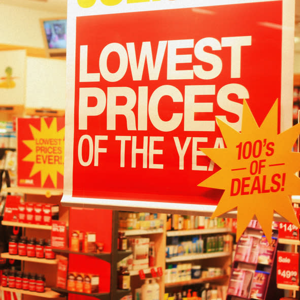 Store with "Lowest Prices of the Year" and "Lowest Prices Ever!" signs displayed prominently, highlighting hundred of deals, shelves stocked with various products in the background