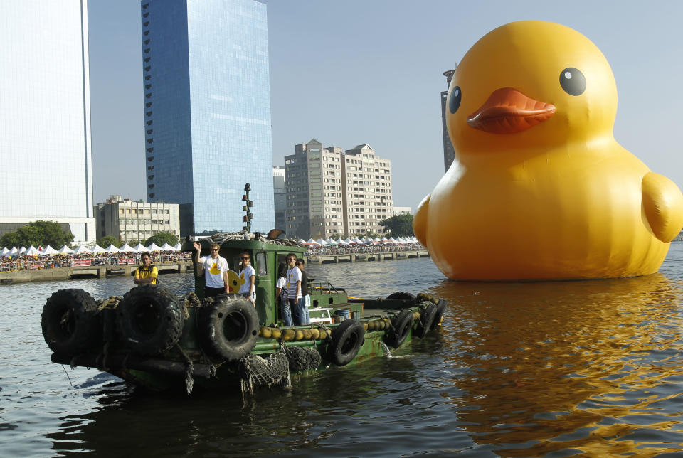 Dutch artist Florentijn Hofman waves to spectators as he and his giant yellow duck art piece arrive in the port of Kaohsiung, Taiwan, Thursday, Sept. 19, 2013. Kaohsiung is the first leg of the Taiwan tour for Hofman's famous 18 meter (59 foot) yellow duck, a gigantic version of the iconic bathtub toy used by children around the world. (AP Photo/Wally Santana)