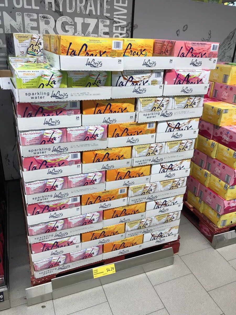 Several boxes of LaCroix cans stacked upon each other in different flavors, at Aldi, Fairfield, Ohio, in a square area, a grey wall in the background